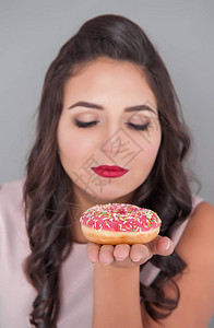 有甜圈的美丽加体型的女人饮食概念图片