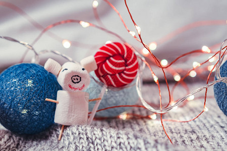 在圣诞装饰的背景下从棉花糖中摘出小猪的图片