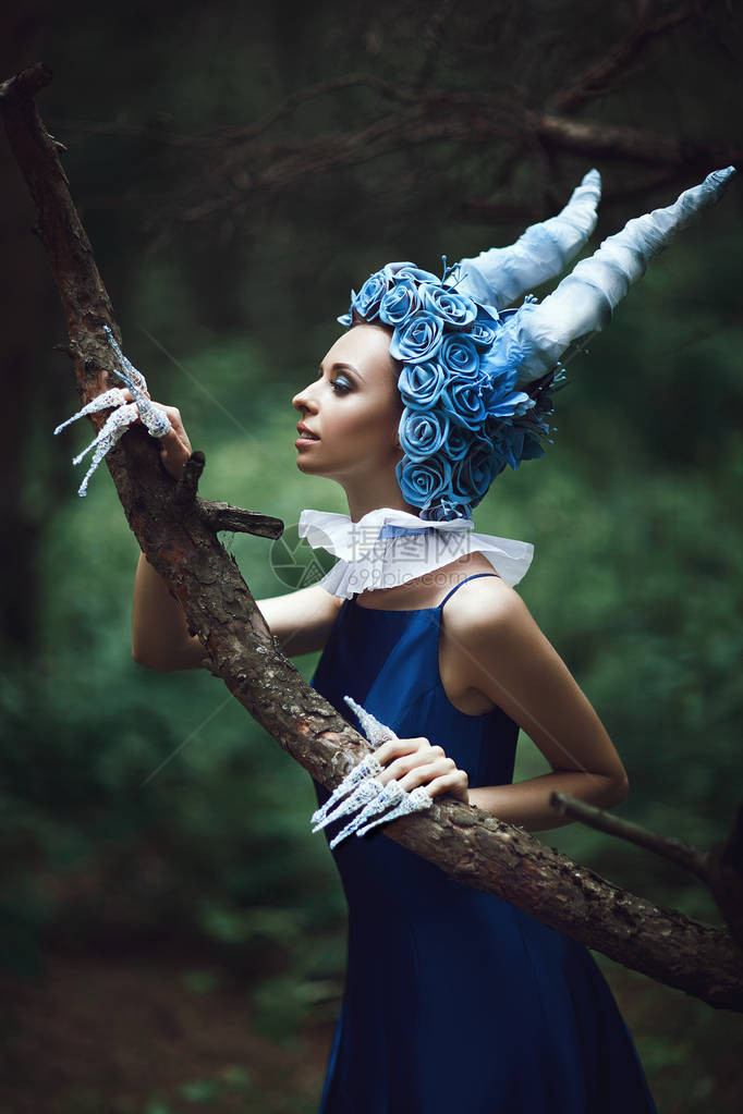 美丽的模特在森林里摆姿势长着蓝色的角图片
