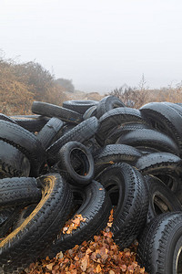 生态概念旧轮胎堆积如山秋天雾盛时在城背景图片