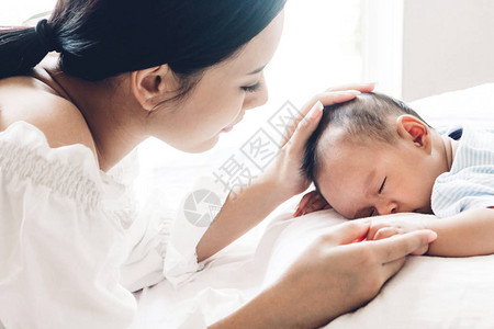 母亲在白床上抱着婴儿的手图片