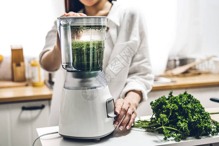 健康女喜欢在家中厨房做绿色蔬菜除毒净化和绿色水果冰淇淋及搅拌机的果汁图片