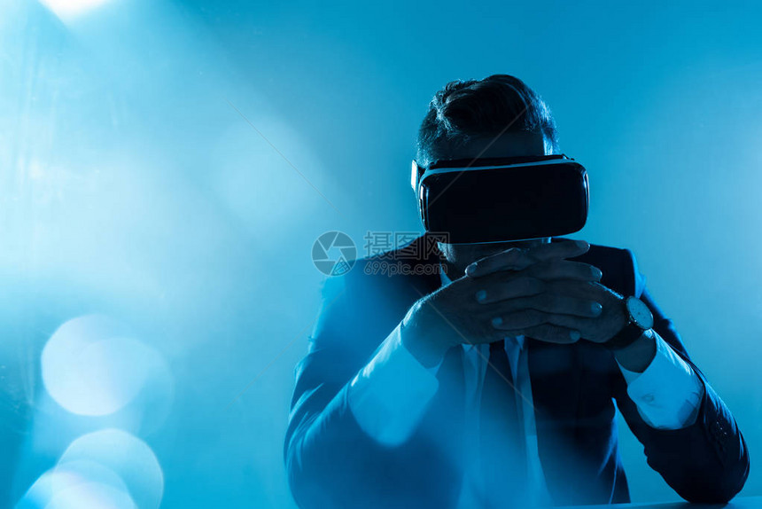 商业在虚拟现实头盔上与世隔绝地坐在蓝色人图片