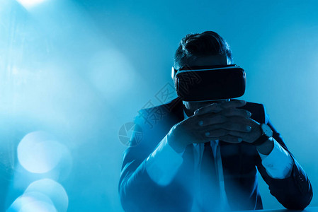 商业在虚拟现实头盔上与世隔绝地坐在蓝色人背景图片
