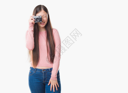 年轻的女在与世隔绝的背景下用老式相机拍照图片