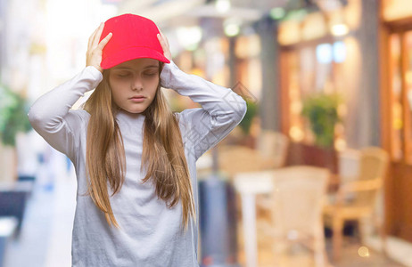 戴着红帽的年轻漂亮女孩与世隔绝的背景因疼痛和偏头痛而头痛绝望和压力大图片