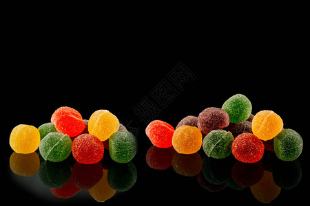 黑色背景上的多彩姿的果酱糖果背景图片