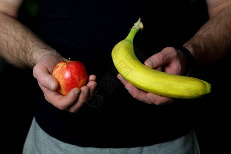 男手握着新鲜多汁的红苹果和黄香蕉图片