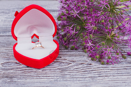 钻石戒指盒和鲜花束鲜花和豪华戒指与木制背景上的钻石浪图片