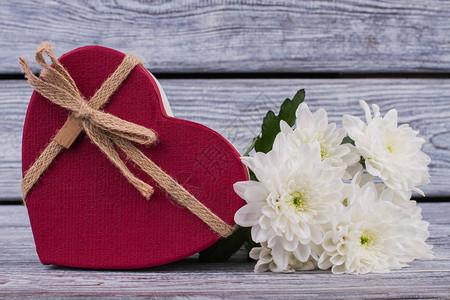 红色心形礼品盒和鲜花情人节礼物盒和木制背景上的图片