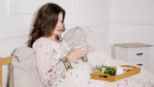 美丽的孕妇坐在床上图片