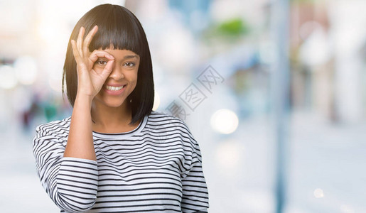 美丽的年轻非洲裔美国女人穿着条纹毛衣在孤立的背景下做着很好的手势图片