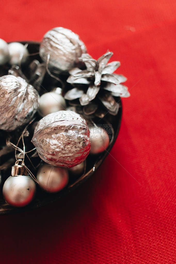 红色背景上带有银球小玩意和松果的圣诞装饰图片