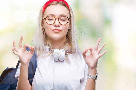 身戴眼镜和背包的金发年轻女学生在孤立的背景中放松图片