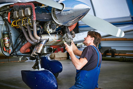 一名服务工人拆除和修理飞机的发动机起动器图片
