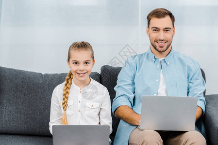 微笑的女儿和父亲坐在沙发上图片