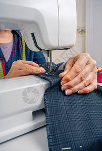 在缝纫机上处理服装的女裁缝手的特写高清图片