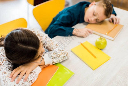 戴眼镜的疲惫学童睡在桌子上图书馆图片