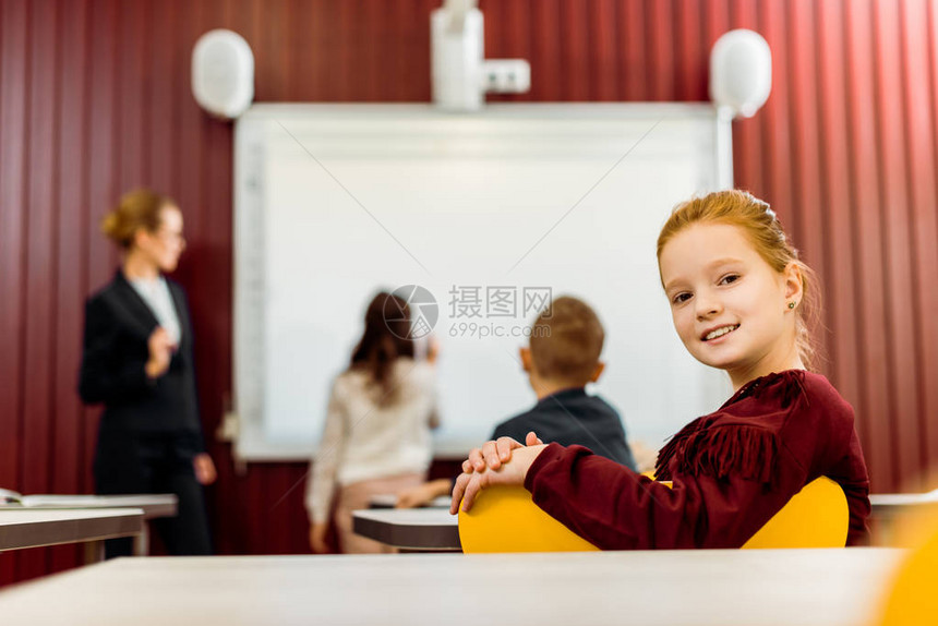 可爱的小学生对着镜头微笑而同学们则图片