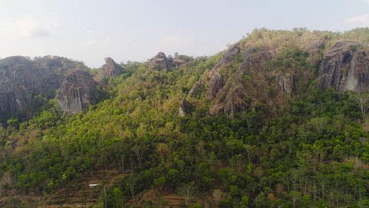 山地景观高耸的悬崖山脉覆盖着绿色的热带森林鸟瞰有大树和绿草的山林印度尼西亚爪哇岛背景图片