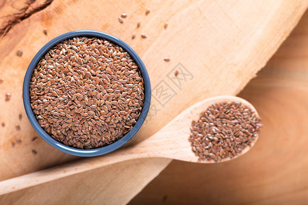 健康食品概念有机亚麻籽在木板上的陶瓷棒中图片