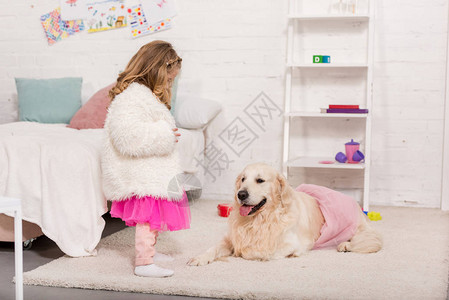 穿着裙子的孩子看着躺在儿童房粉色裙子地毯图片