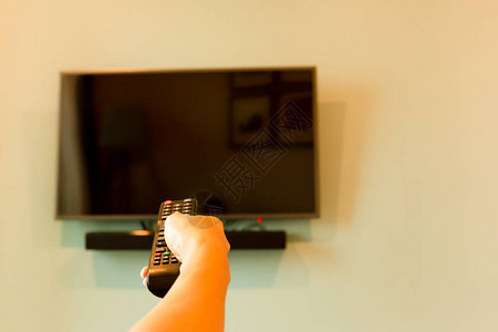 手握电视遥控器在宽屏幕电视机前用图片