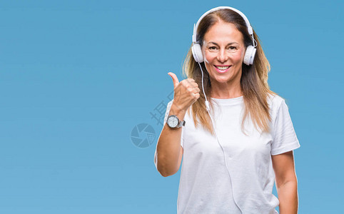 中年的西班牙裔女在孤立的背景下听音乐时佩戴耳机图片
