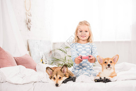 可爱的小孩坐在床上与PembrokewelshCorgi狗在一起图片
