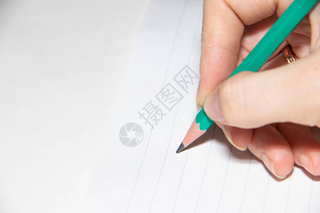 用铅笔在纸上写字的女手特写图片