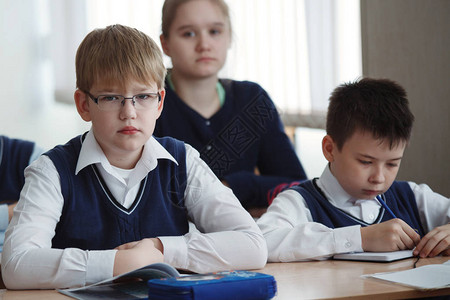在学校的书桌坐着戴眼镜的年轻小伙将教师的任背景图片