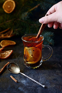 圣诞茶用橙子和香料选择焦点托盘上的热辣茶与针叶树的枝深色木质背景图片