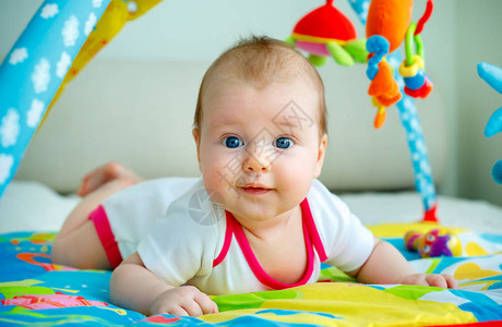 可爱的女婴在多彩游戏垫上玩具得开心图片