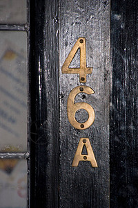 黑色木门上的黄铜门牌号46A背景