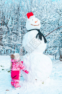穿着粉红冬衣的金发小孩看着大雪图片