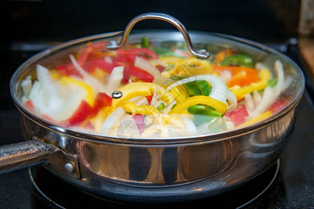 在厨房锅里煮香肠洋葱和红黄绿青椒图片