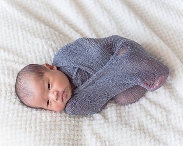 刚出生的亚洲男婴裹着紫色针织马海毛6天大婴儿躺在床上图片