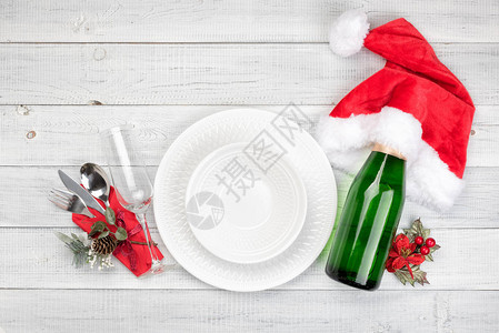 圣诞餐桌设置与一瓶香槟玻璃白色背景上的红色v顶视图顶视图片