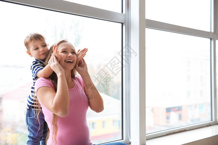 年轻孕妇在窗户旁边玩耍与可爱的图片