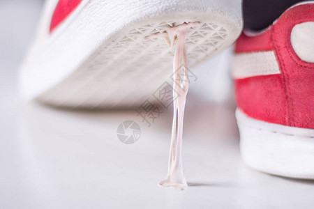 踩在白色表面上的口香糖的运动鞋运动鞋底上的粘泡糖粘概念特写图片