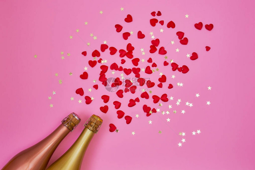 两瓶红心香槟和粉红色彩的金情人节庆典的概念是平坦图片