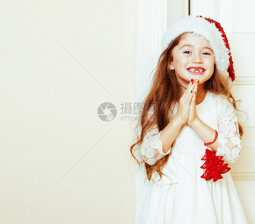 圣诞老人红色帽子等待圣诞礼物的可爱小女孩微笑可爱的孩子白色新礼服图片