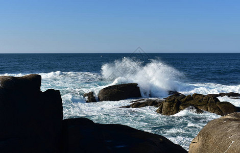 大浪冲向岩石蓝海有白泡沫阳光明媚的一天西图片