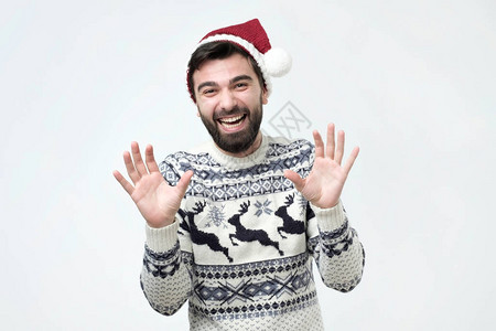 戴着圣诞帽的兴奋迷人的快乐男人微笑着大口喘着粗气图片