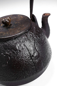 浅色背景中古董铁茶壶的特写图片