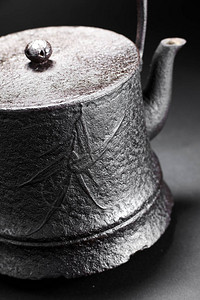 深色背景中古董铁茶壶的特写图片
