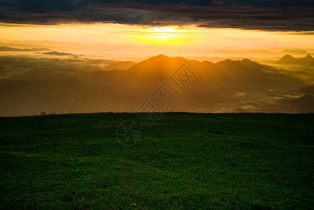 日出景观戏剧天空云山背景上山绿草上的早晨美丽的日出图片