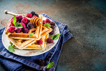 带浆果和蜂蜜的自制贝吉亚松饼用深蓝色图片