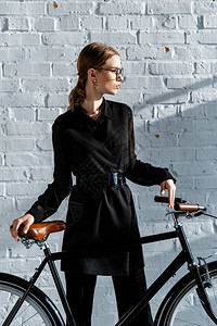 黑衣黑色自行车和棕马鞍的有色妇背景图片