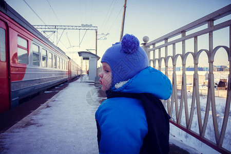 穿着蓝色冬季夹克和火车附近帽子的可爱caucasia图片